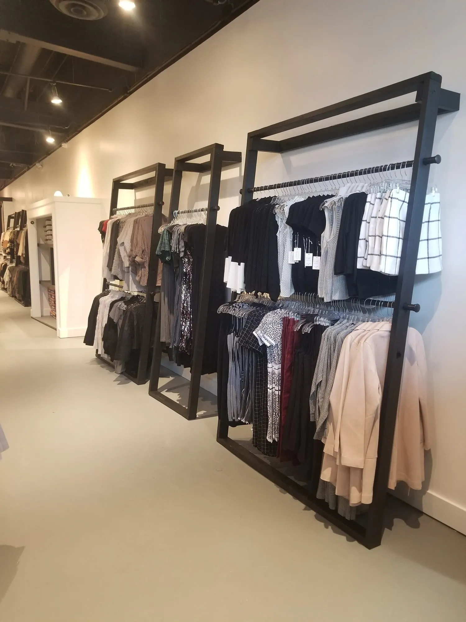 Finished boutique interior with black steel clothing racks against white walls