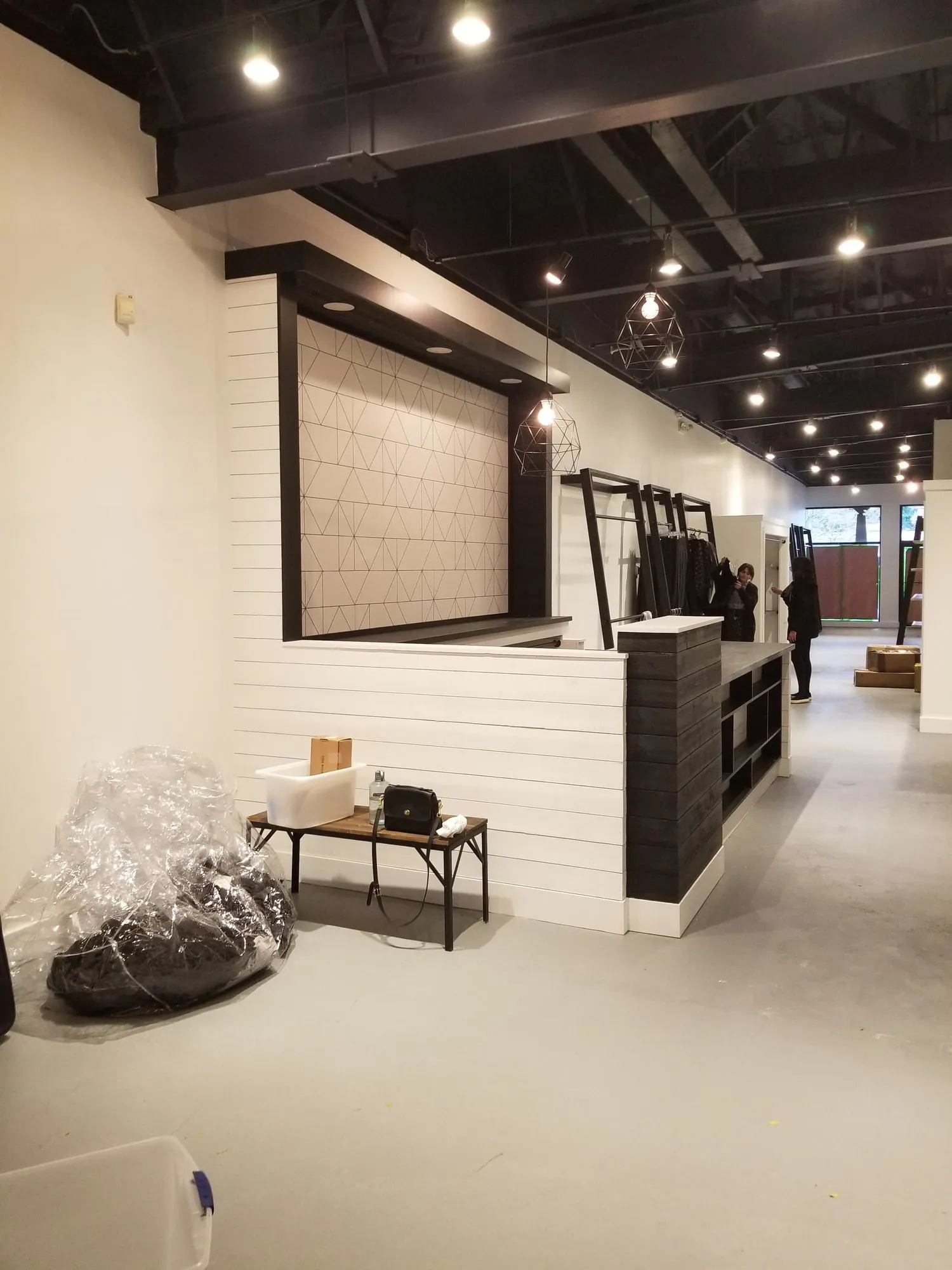 Retail checkout counter clad in white shiplap with black display shelving