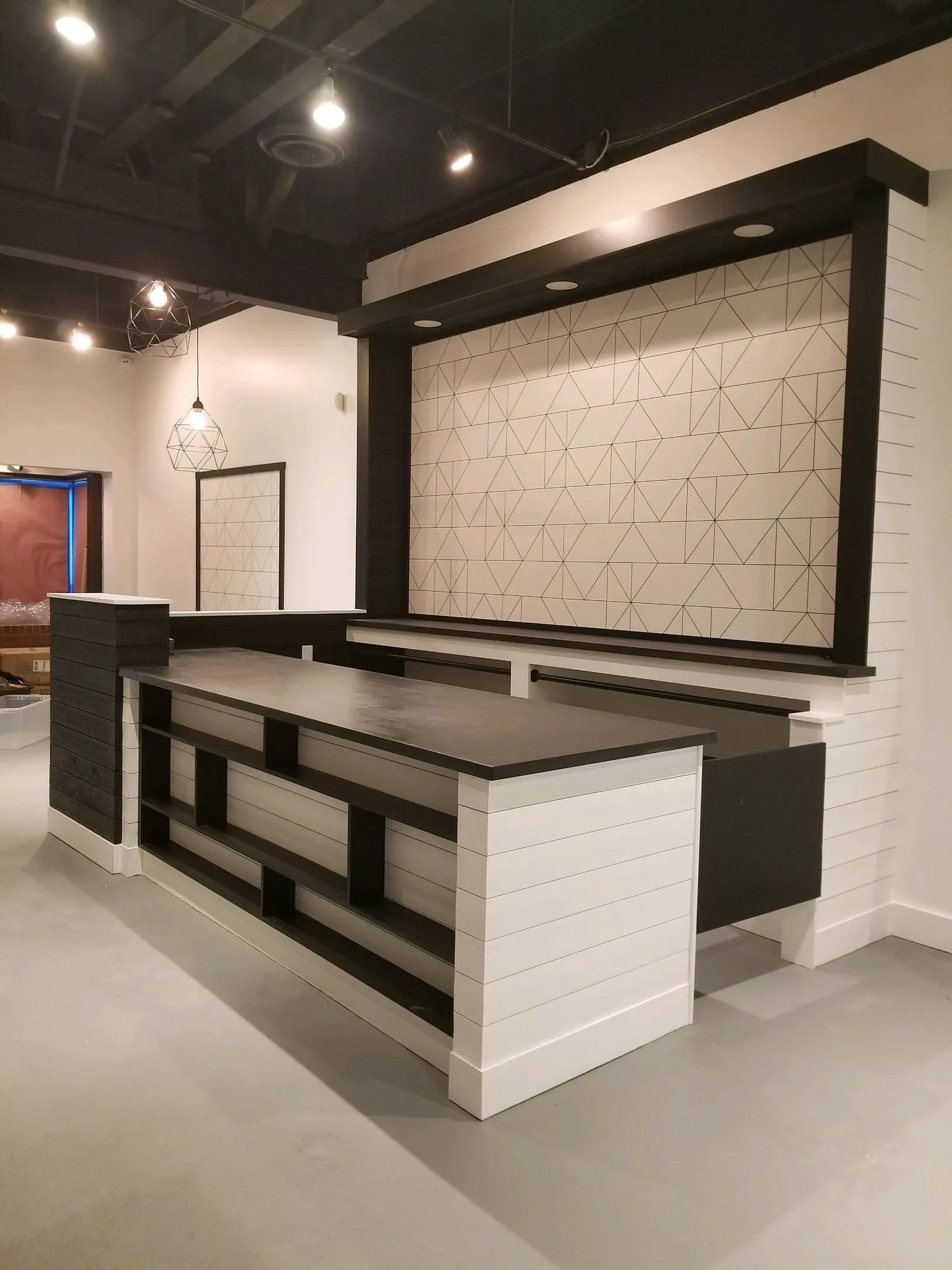 Black and white retail counter with geometric tile feature wall behind