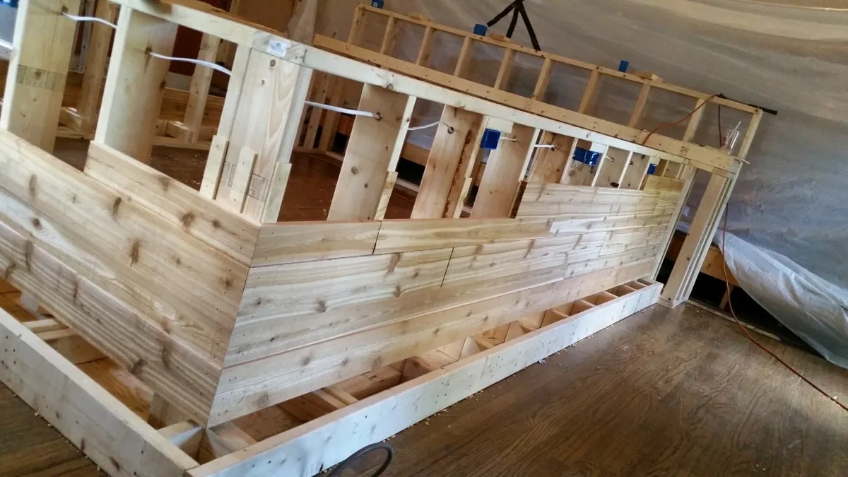 Reclaimed wood cladding being installed along the face of a new bar