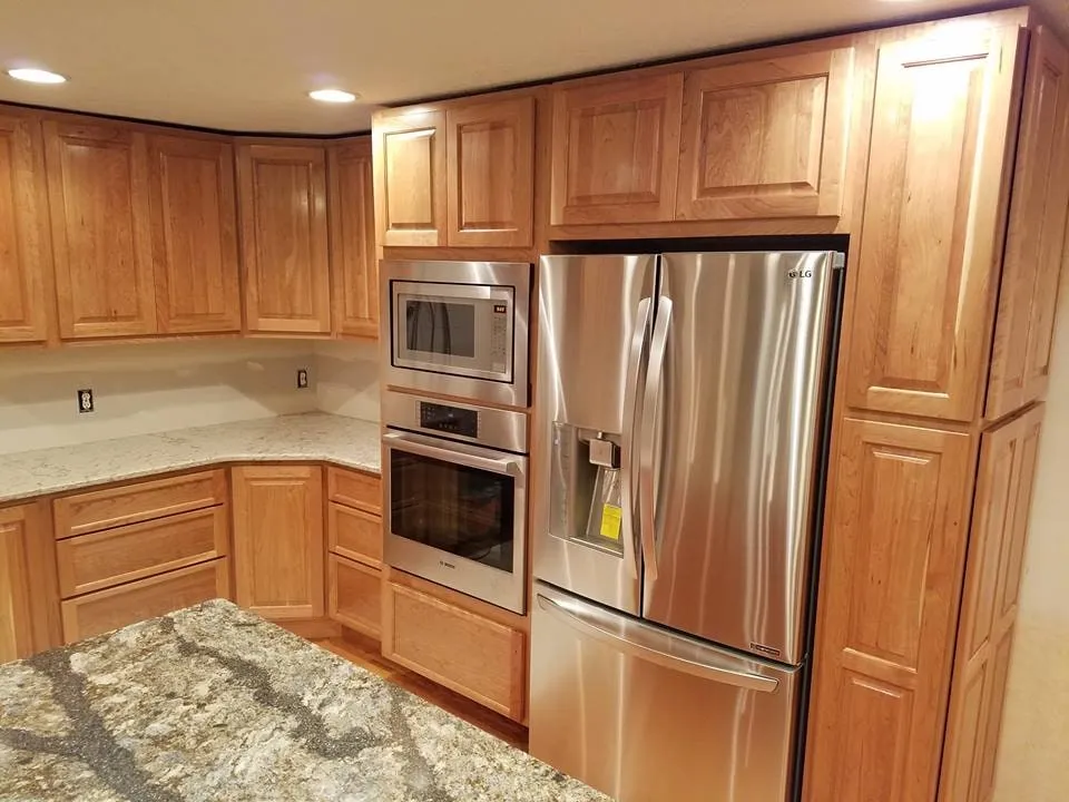 Kitchen renovation with full-height cherry cabinetry, stainless refrigerator and granite counters