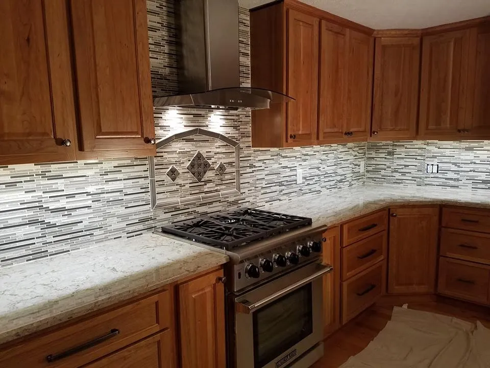 Kitchen with stainless range hood, professional gas range and a patterned tile backsplash