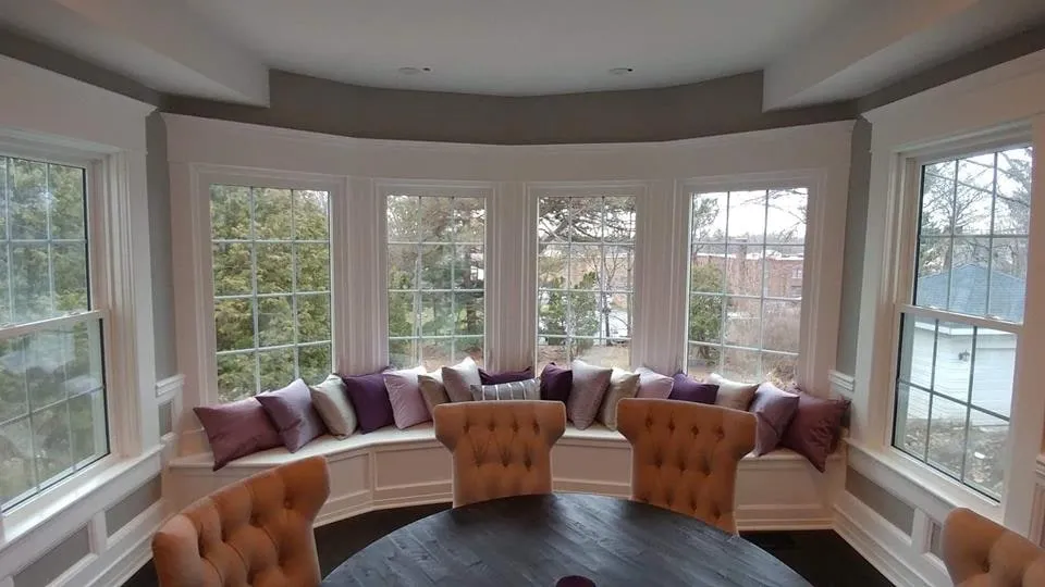 Curved bay window with a built-in cushioned bench seat and upholstered armchairs