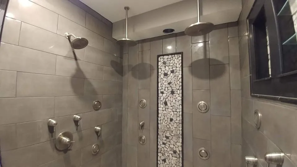Tiled walk-in shower with dual rain heads, body sprays and a pebble mosaic accent strip