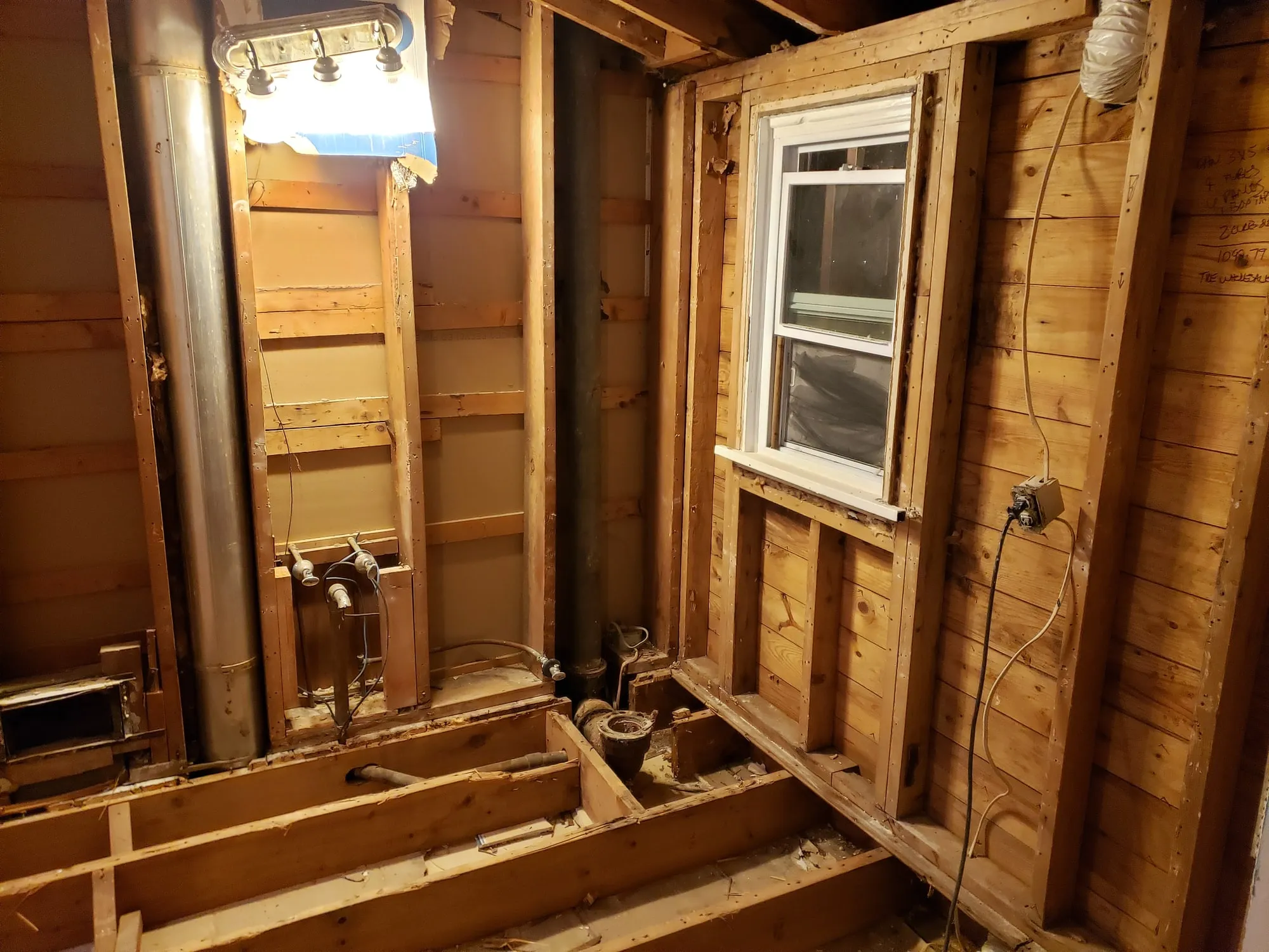 Bathroom framing and rough plumbing exposed during demolition
