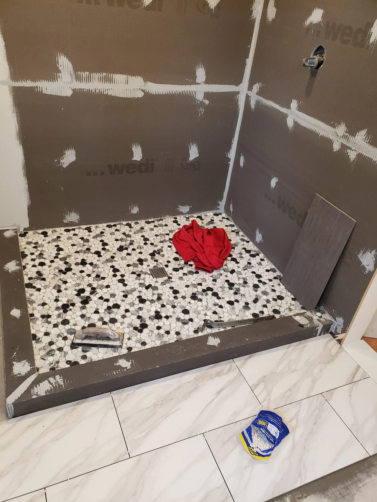 Pebble mosaic shower floor being set into the waterproofed pan