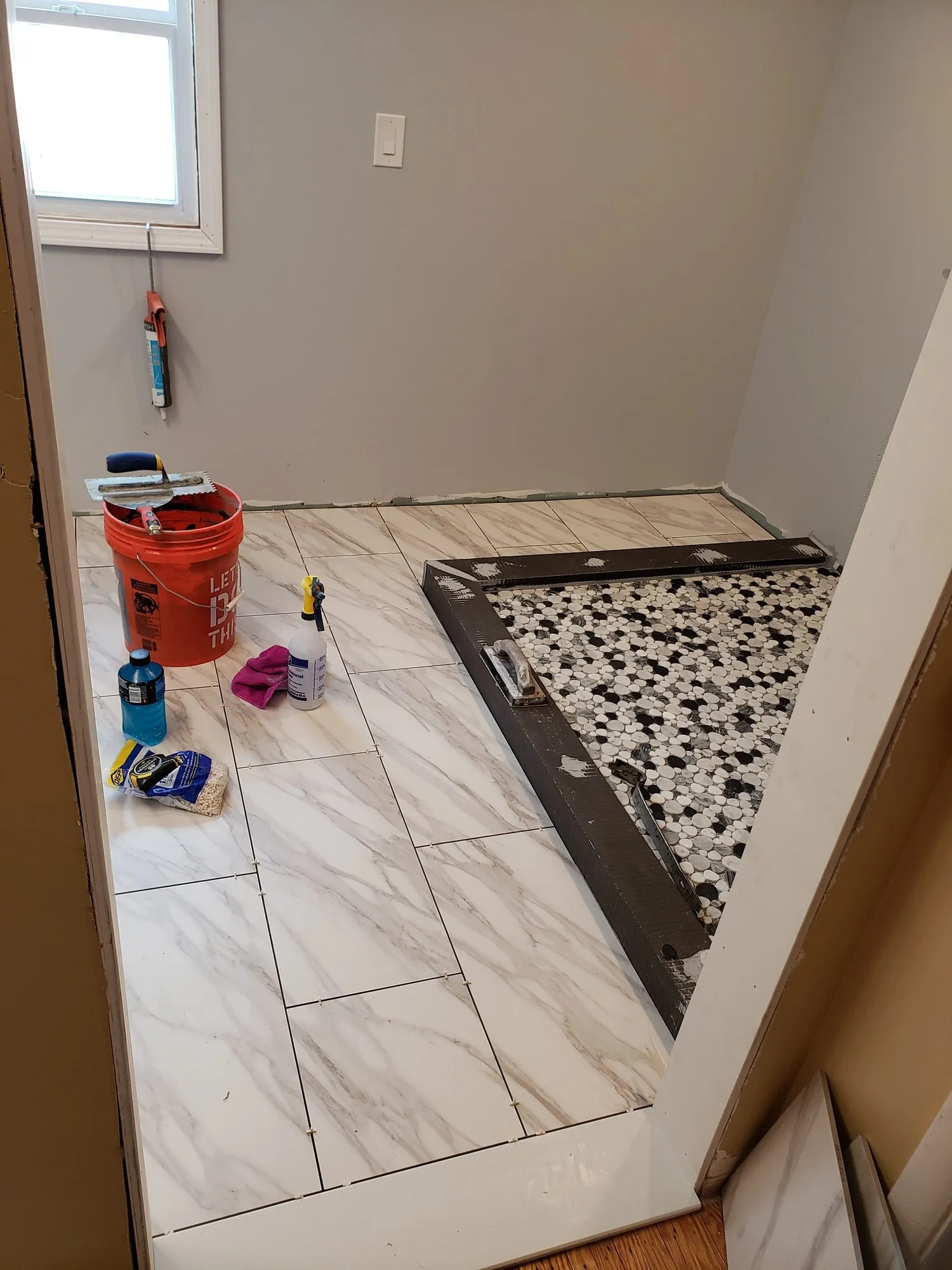 Bathroom floor tile installation in progress around a new shower base