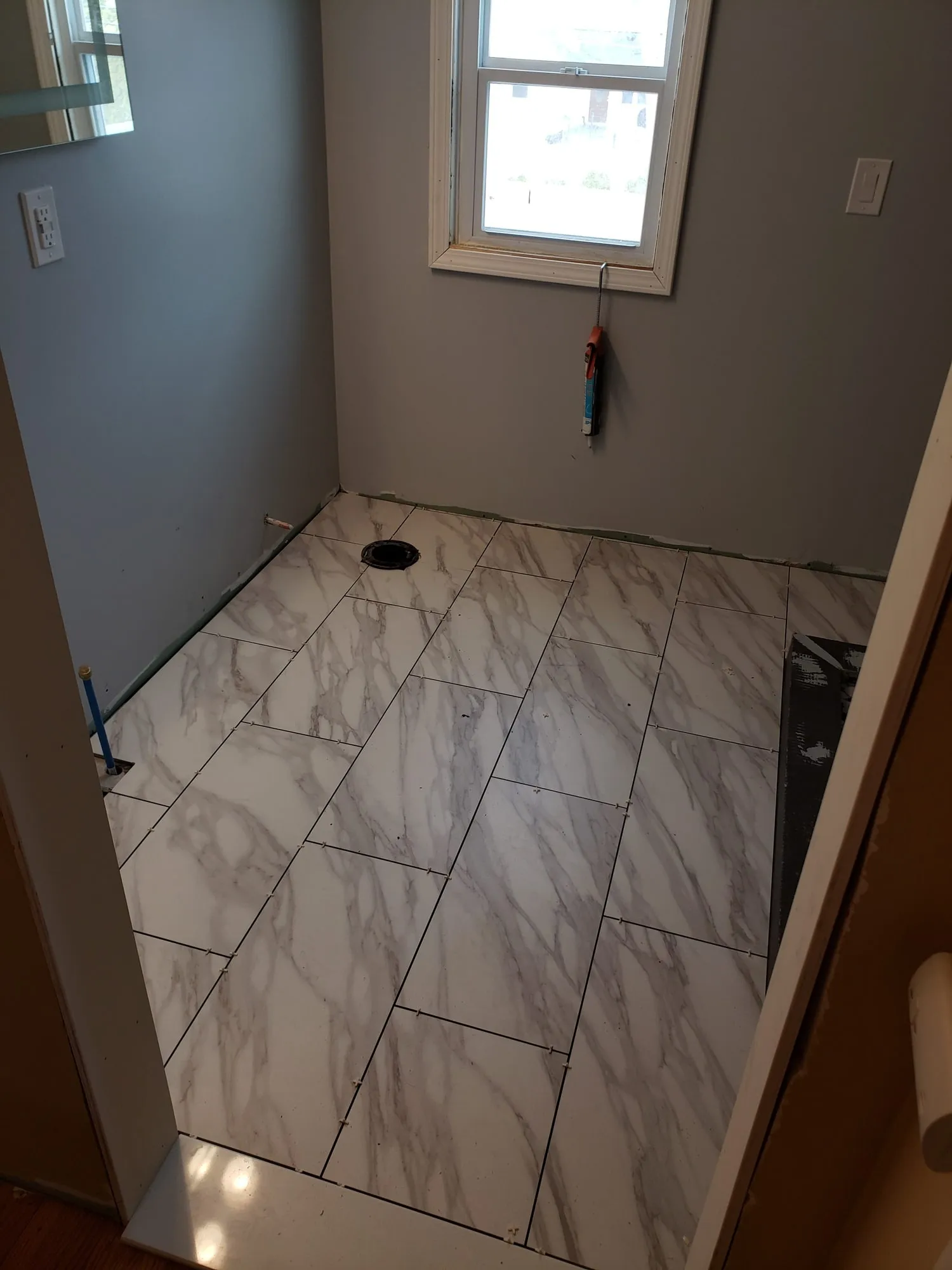 Marble-look floor tile laid up to a newly framed shower curb