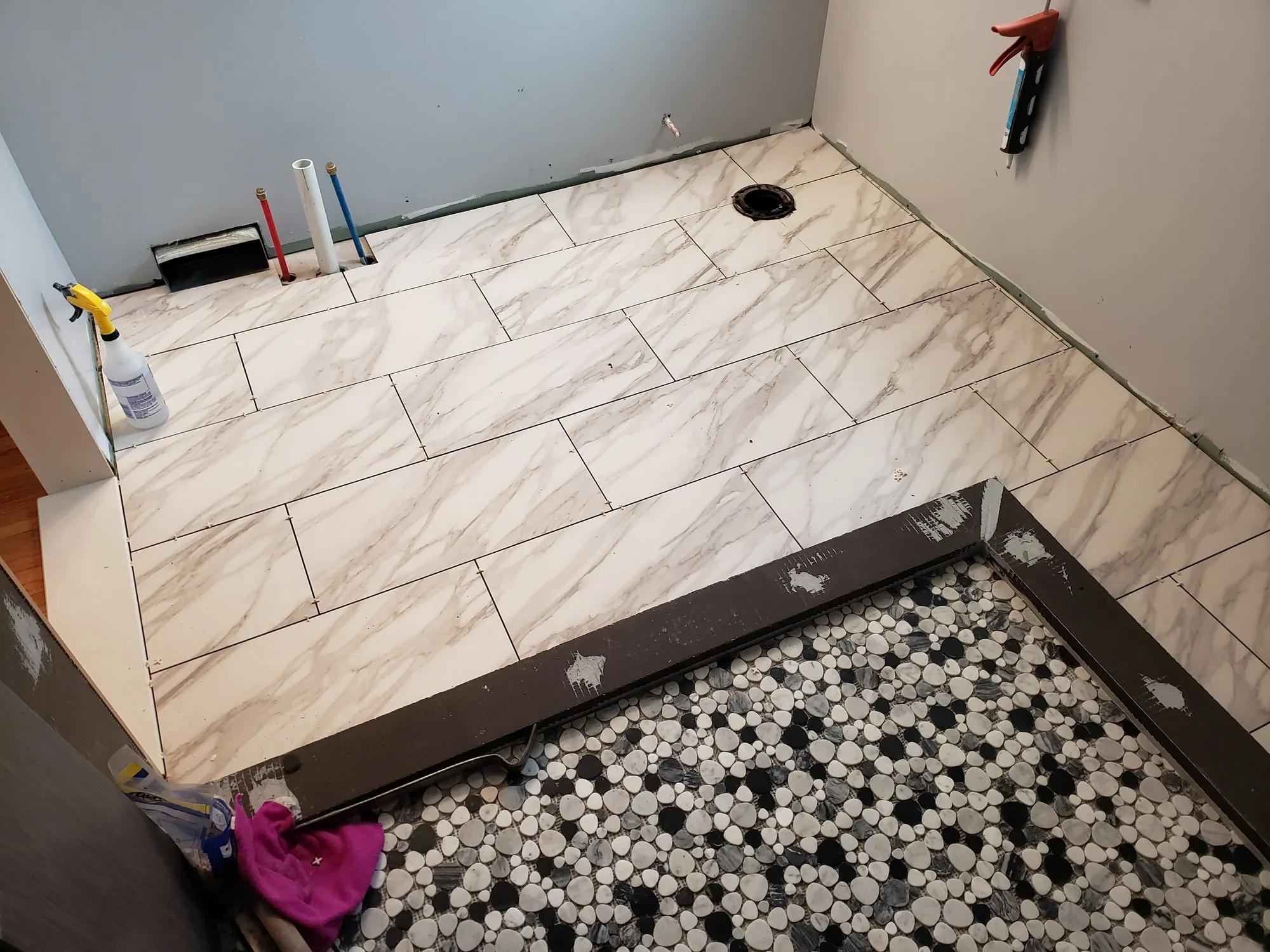 Large-format floor tile installed across a bathroom during remodeling