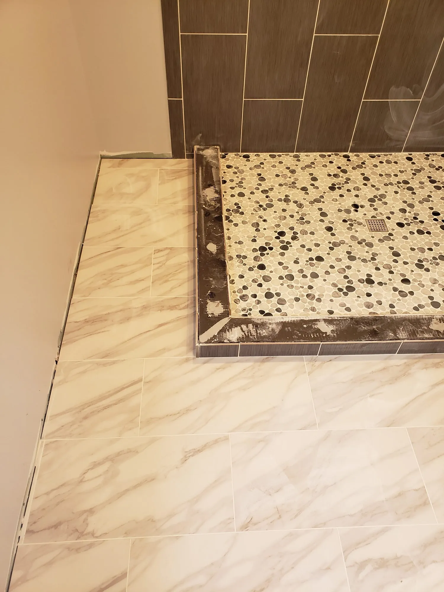 Finished pebble mosaic shower floor with a tiled curb