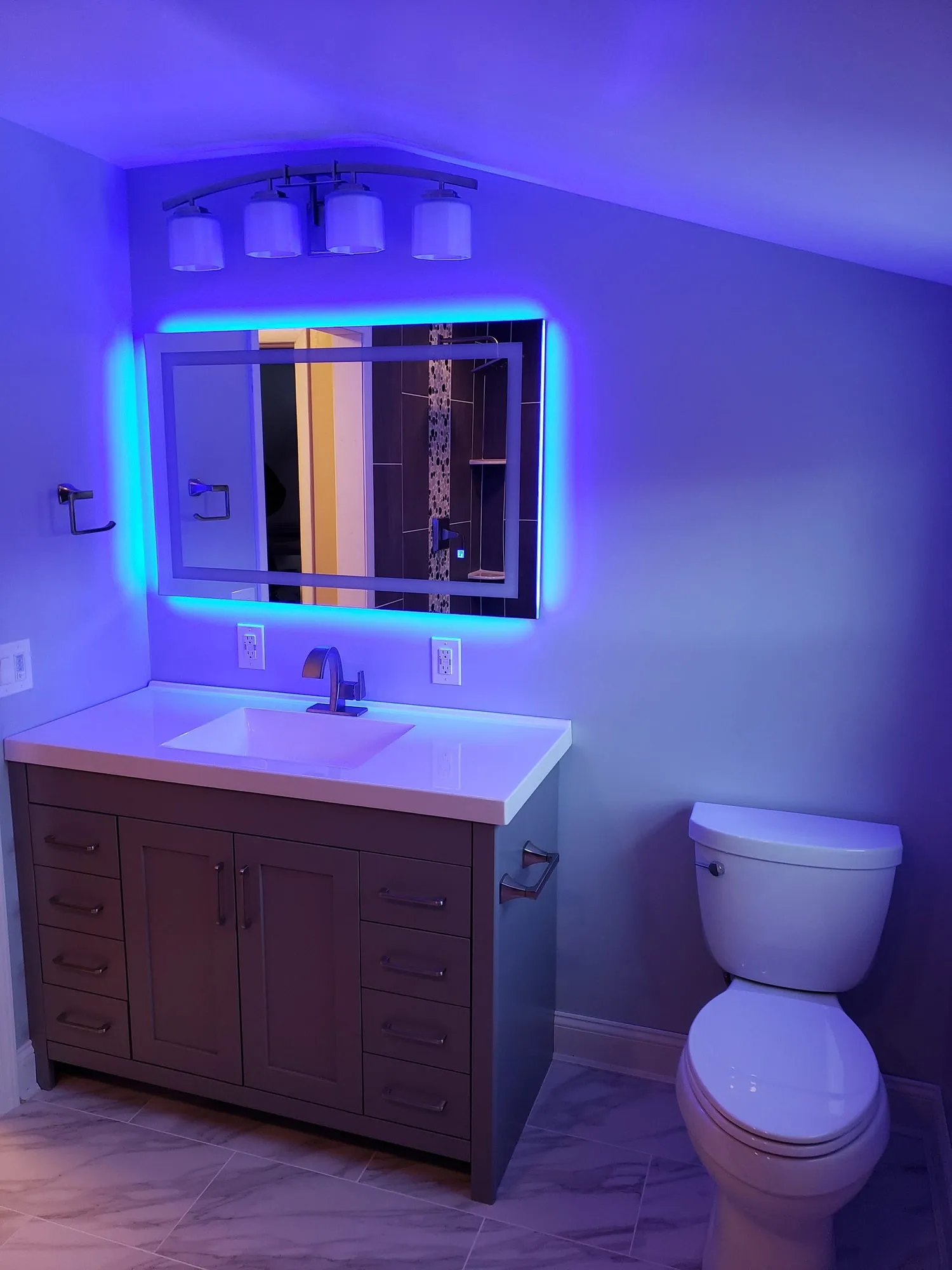 Backlit LED mirror above a floating vanity in a completed bathroom