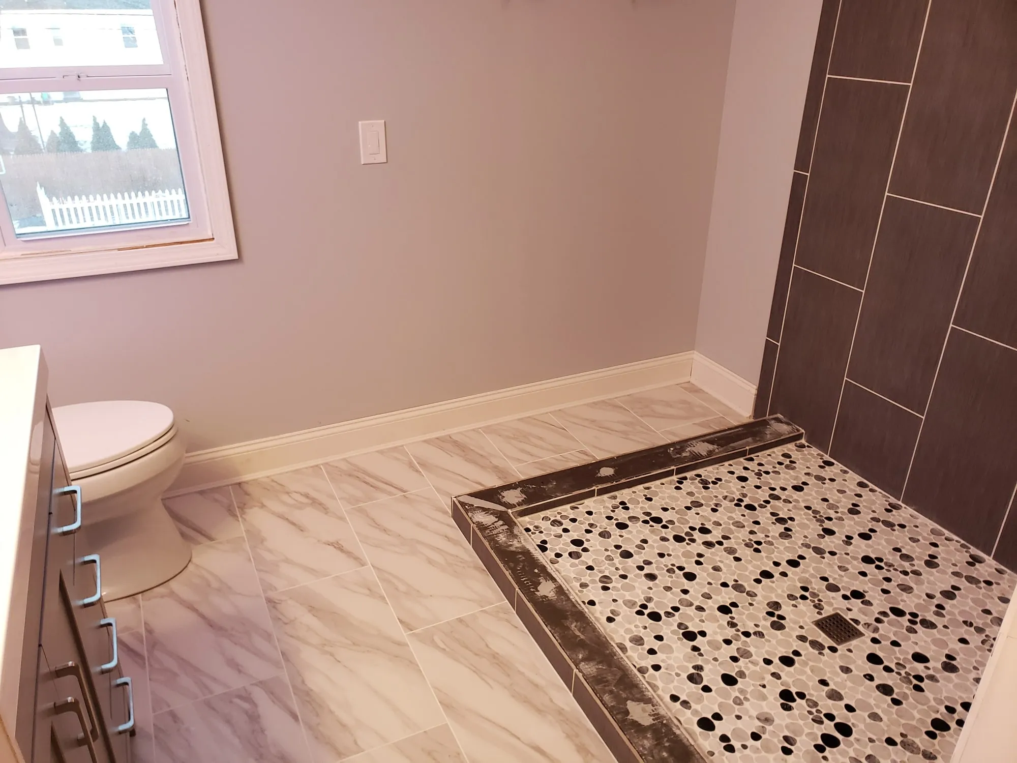 Completed bathroom floor with pebble mosaic inlay at the shower entry